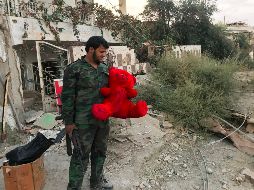 Un soldado carga un oso de peluche recuperado de entre los escombros en Deir al Zur. AFP/STRINGER