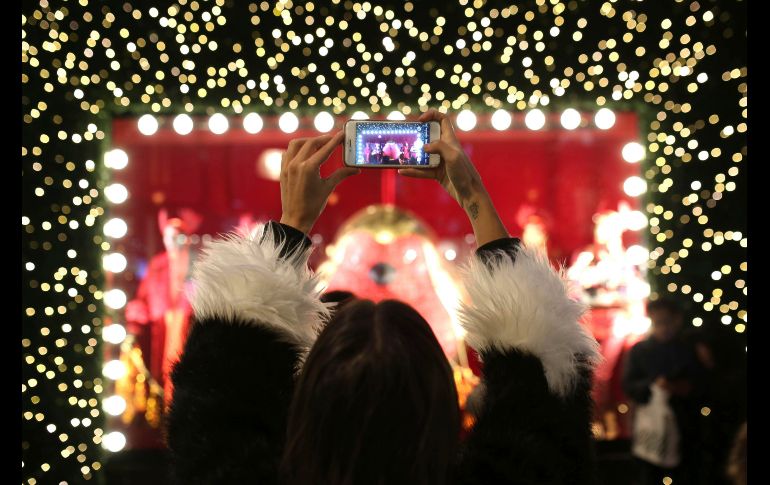Una mujer capta un aparador luego de que se encendieran las luces navideñas en la calle de tiendas Oxford, en Londres. AP/D. Parry
