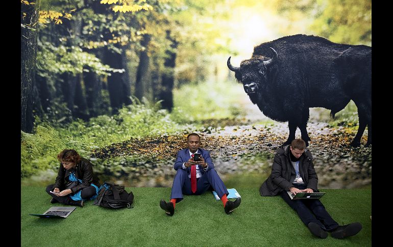 Asistentes a la Cumbre del Clima en la ciudad alemana de Bonn toman un descanso junto a un póster. AP/DPA/O. Berg