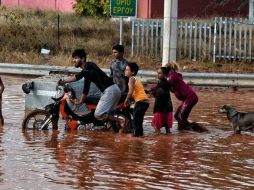 Varias personas transitan por una de las calles inundadas. EFE/Y. Kemmos