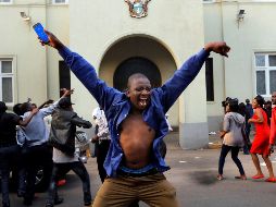 A man holds up the national flag of Zimbabwe as Zimbabwean soldiers a - A man holds up the national flag of Zimbabwe as Zimbabwean soldiers are celebrated by citizens in the streets in Harare, on November 21, 2017 after the resignation of Zimbabwe