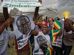 Simpatizantes de Emmerson Mnangagwa, muestran fotografías de él y aplauden cuando llegan para mostrar su apoyo en la base de la Fuerza Aérea de Manyame. AP/B. Curtis