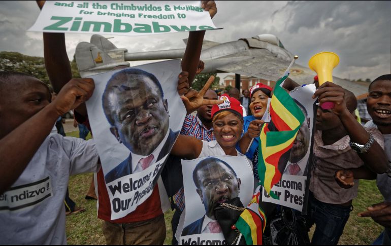 Simpatizantes de Emmerson Mnangagwa, muestran fotografías de él y aplauden cuando llegan para mostrar su apoyo en la base de la Fuerza Aérea de Manyame. AP/B. Curtis