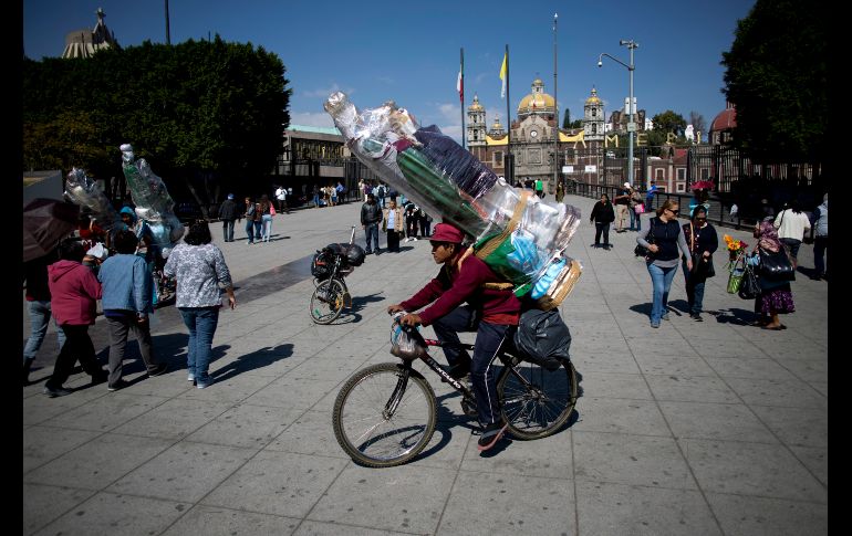 Un muchacho carga dos figuras de la Virgen María mientras pasa en su bicicleta afuera de la Basílica de Guadalupe. AP / E. Verdugo