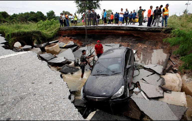 Oficiales tailandeses inspeccionan una carretera derrumbada por las inundaciones causadas por las fuertes lluvias en el distrito de Thepha. EFE/A. Wangni