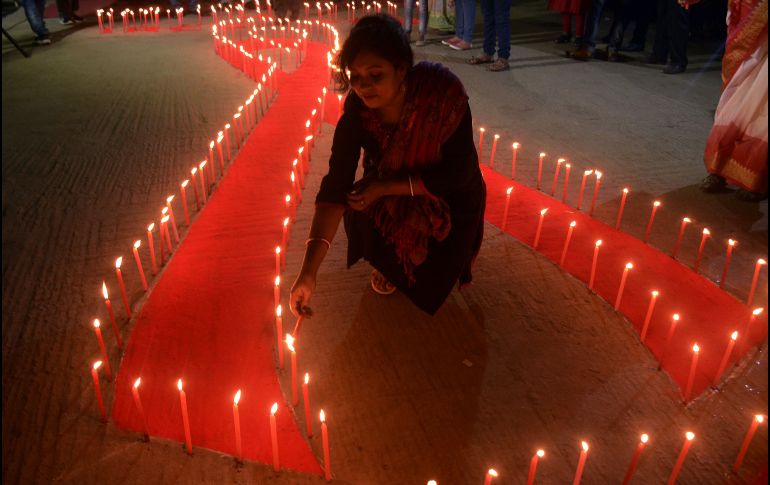 Voluntarios encienden velas colocadas en forma de un listón rojo en Agartala, India, en la víspera del Día Internacional de Lucha contra el Sida. AFP/A. Dey