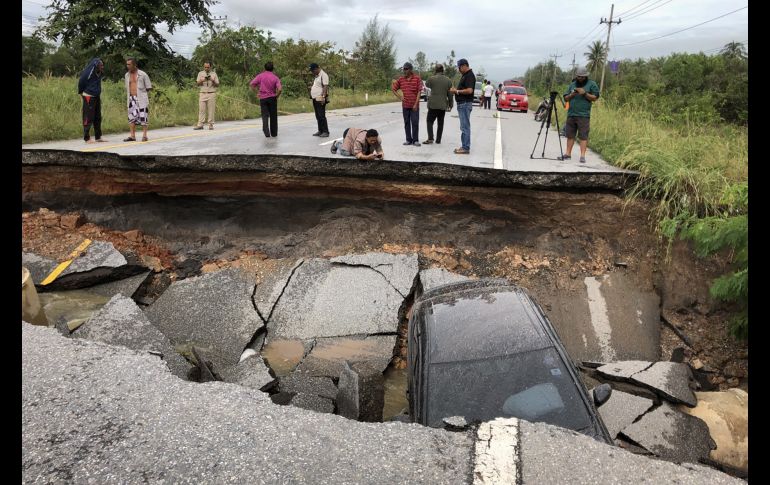 Personas observan una carretera que colapsó tras inundaciones en Songkhla, Tailandia. AFP/T. Meringing