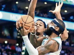 Kyrie Irving. La estrella de los Celtics intenta encestar ante la marca de John Henson, durante el juego de ayer entre Boston y los Bucks de Milwaukee. AFP