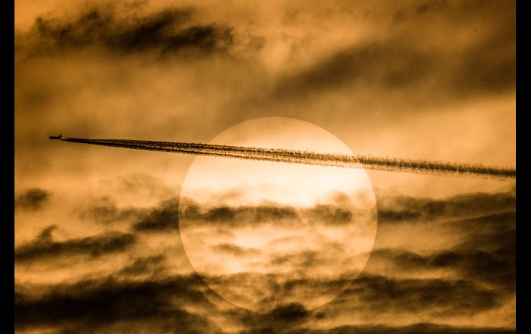 Un avión de pasajeros vuela con del Sol de fondo en Rangún, Birmania.