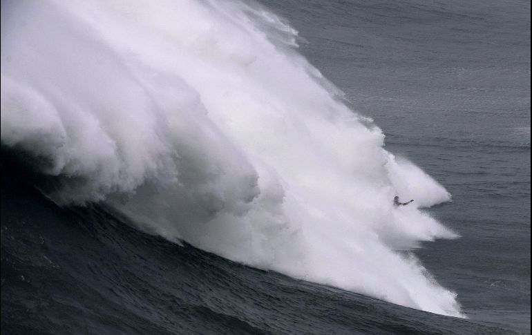 Un participante en una sesión de surf se ve entre una ola en Nazare, Portugal. AFP/F. Leong