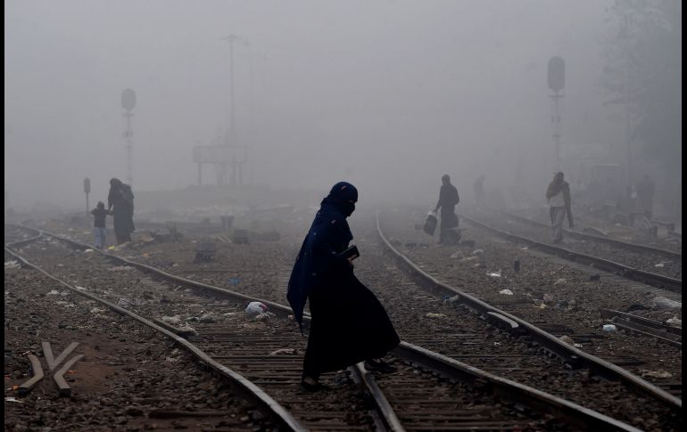 Una pakistaní camina por líneas de tren en Lahore, a través de una densa niebla. AFP/A. Ali