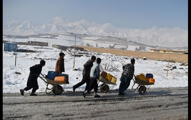 Afganos transportan contenedores de agua luego de la primera nevada de la temporada en el distrito Paghman. AFP/W. Kohsar