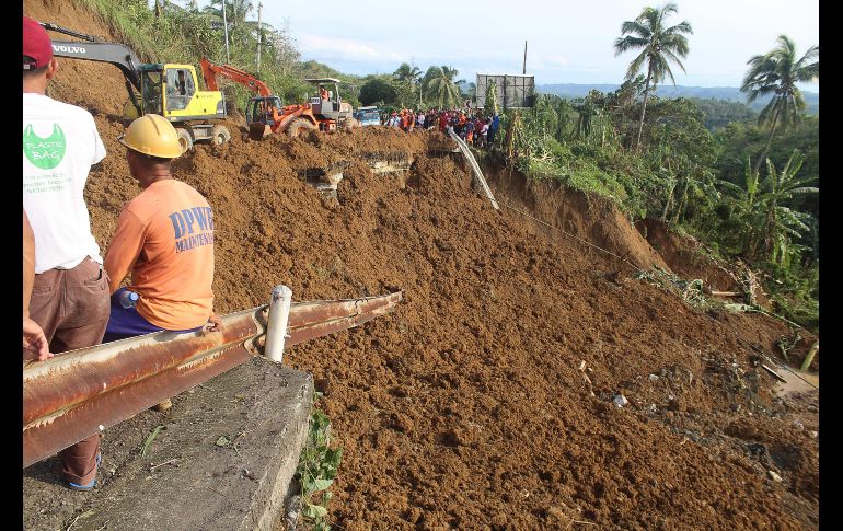 Con maquinaria pesada se removía tierra en la orilla de una carretera colapsada.