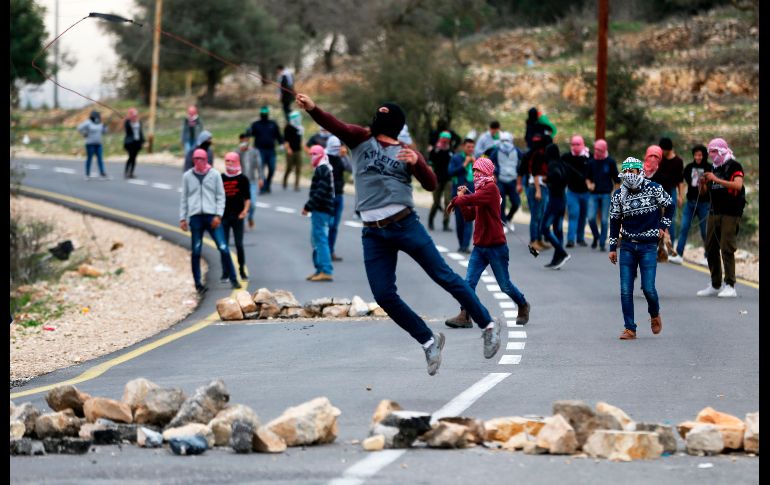 Un palestino arroja piedras durante enfrentamientos con fuerzas de seguridad israelíes en el punto de revisión de Atarot, en Ramallah. AFP/A. Momani