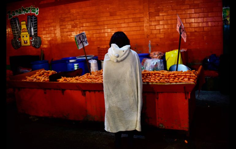 Una mujer vende zanahorias.