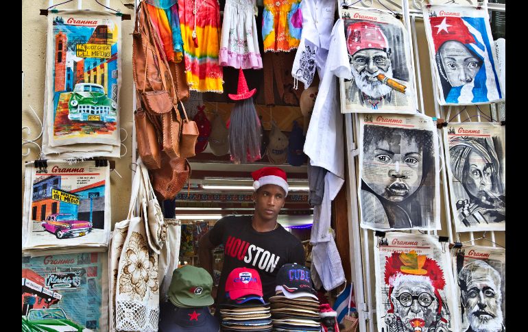 Un joven con un gorro navideño permanece en la entrada de un negocio de artesanías en La Habana, Cuba. EFE/E. Mastrascusa
