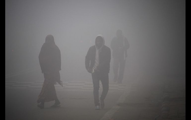 Gente camina por una calle de Nueva Delhi, India, entre una densa capa de esmog. AFP/D. Faget