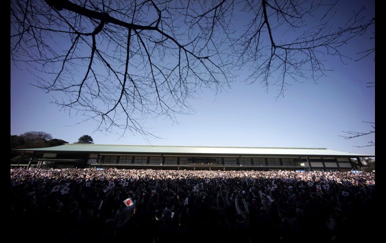 Habitantes ondean banderas nacionales mientras el emperador de Japón, Akihito, y su familia saludan desde el balcón del Palacio Imperial en Tokio, Japón. AP/E. Hoshiko