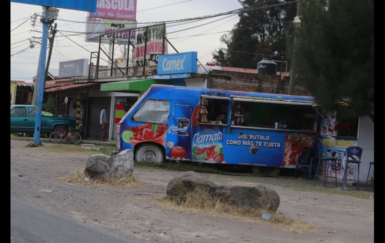 Vehículos de venta de botana y bebidas alcohólicas continúan instalados en el acotamiento de la carretera. El deterioro es evidente tanto en superficie como en señalética. EL INFORMADOR / G. Gallo