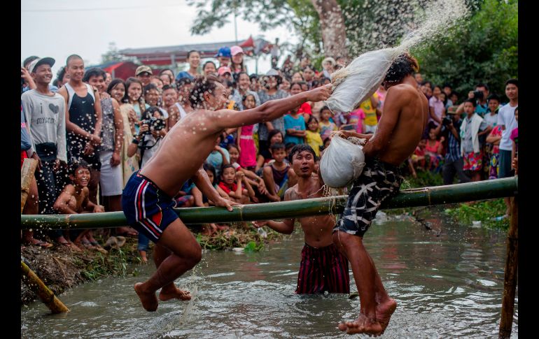 Jóvenes juegan una guerra de alhomadas sobre una vara de bambú, como parte de las festividades por el día de la independencia en Rangún, Birmania. AFP/Y. Aung Thu