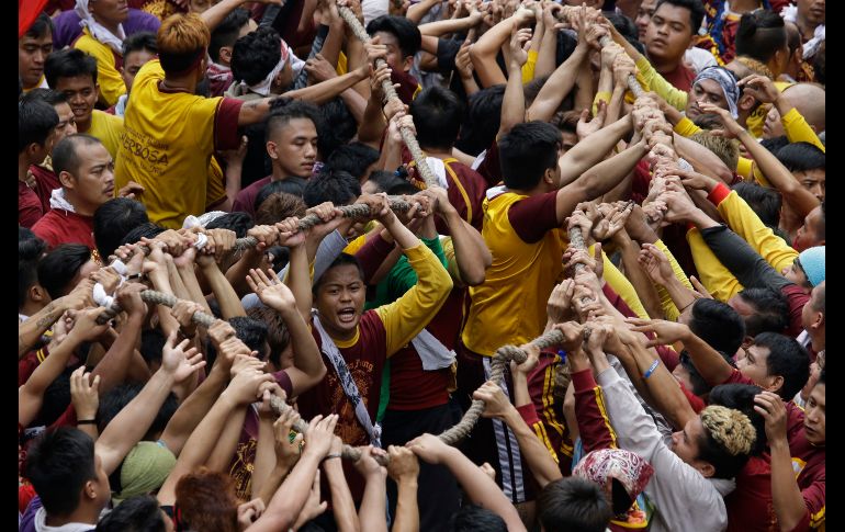 Fieles católicos se empujan para agarrar la cuerda que jala el carruaje con la imagen del Nazareno Negro, durante la multitudinaria procesión por la festividad religiosa. AP/A. Favila