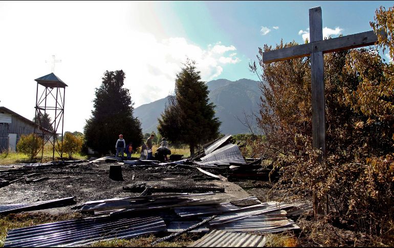 Personas buscan entre los restos del templo Santa Juana en la comuna de Cunco, región de la Araucanía.