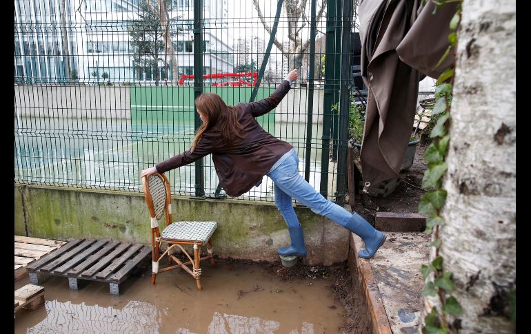 Una mujer maniobra para evitar el agua en Ile de la Grande Jatte, al oeste de París. AFP/G. Van Der Hasselt