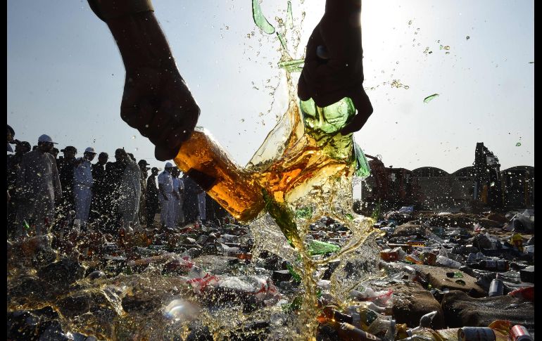 Un oficial de aduanas rompe botellas de licor decomisadas, durante una ceremonia en Karachi, Pakistán, en el marco del  Día de Aduanas. AFP/A. Hassan