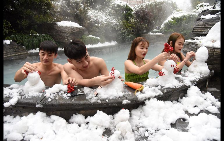 Visitantes a una alberca en una zona de aguas termales en Hangzhou, China, hacen monos de nieve. En la región se registran fuertes nevadas. AFP