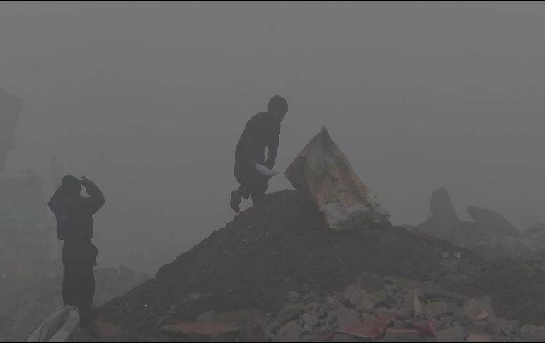 Un niño busca materiales para reciclar en una calle de Lahore, Pakistán, en una mañana con neblina. AFP/A. Ali