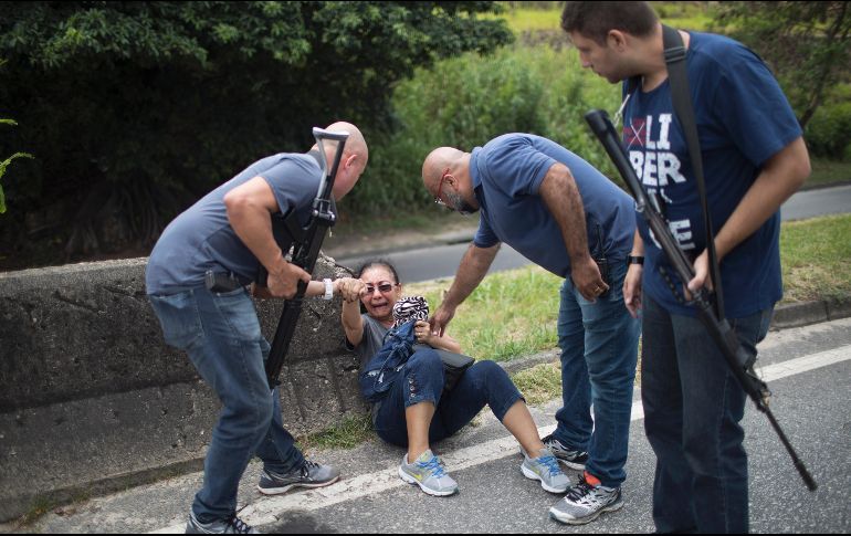 Policías auxilian a una mujer que se refugiaba durante un enfrentamiento entre presuntos narcotraficantes y policías en Río de Janeiro, Brasil. AP/L. Correa