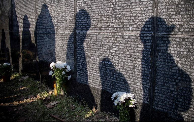 Sombras de personas se proyectan en el monumento que contiene los nombres de las víctimas del gobierno comunista, en una misa en Sofía, Bulgaria, realizada en el aniversario de las primeras muertes del régimen, el 1 de febrero de 1945. AFP/N. Doychinov