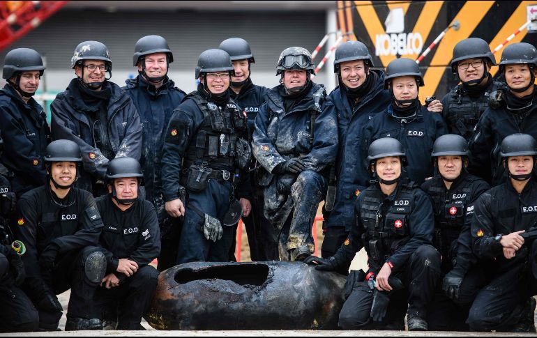 El experto en desactivación de bombas Adam Roberts (centro a la der.) y compañeros de la unidad  antiexplosivos posan con una bomba de la Segunda Guerra Mundial desactivada, tras su hallazgo en un sitio en construcción en Hong Kong. AFP/A. Wallace
