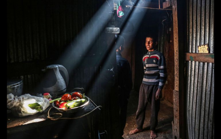 Palestinos platican en su vivienda hechiza sin electricidad por los cortes de energía, en el campamento de refugiados de Rafah, en la Franja de Gaza. AFP/S. Khatib