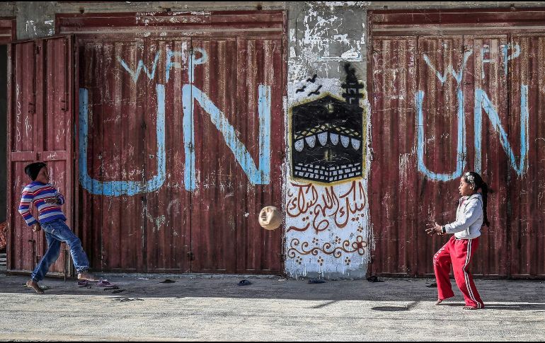 Palestinos juegan afuera de un centro de distribución de alimentos de la ONU en el campamento de  refugiados de Rafah, en la Franja de Gaza. AFP/S. Khatib