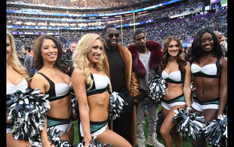 El rapero Sean Combs (c i) y su hijo Christian Casey Combs posan con porristas de Eagles.