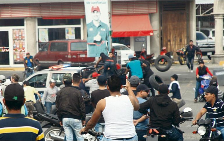 En una imagen de las protestas se puede apreciar que algunos manifestantes bajan llantas de una patrulla. ESPECIAL