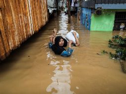 Una mujer y un niño intentan desplazarse, con el agua casi cubriéndolos por completo. EFE/M. Irham