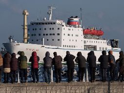 Varios curiosos observan la llegada del ferri Mangyongbong-92, donde viaja la orquesta. AFP/E. Jones