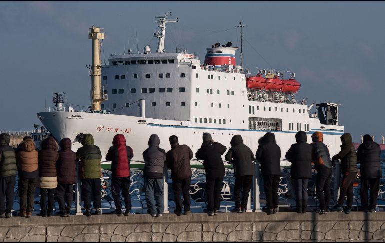 Varios curiosos observan la llegada del ferri Mangyongbong-92, donde viaja la orquesta. AFP/E. Jones