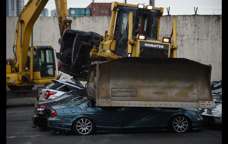 Un bulldozer aplasta automóviles de lujo en un terreno de Aduanas en Manila, Filipinas. Las unidades fueron decomisadas tras su ingreso ilegal al país. AFP/T. Aljibe