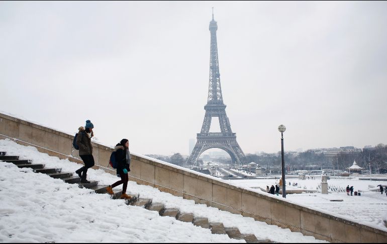 Personas bajan por una escalera con la torre Eiffel en el fondo. Se trata de la mayor nevada en 30 años en la capital francesa. AP/T. Camus