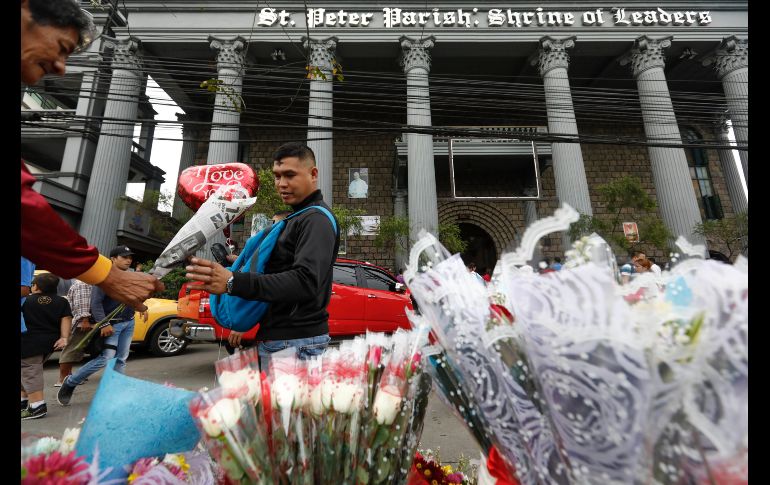 Un hombre con ceniza en la frente compra flores para San Valentín en Quezon City, Filipinas.
