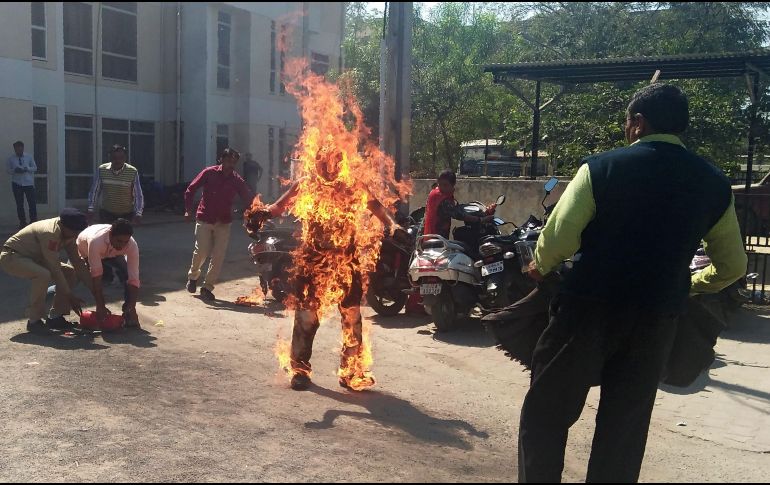 Policías intentan salvar a Bhanubhai Vankar, quien se prendió fuego el 15 de febrero en Patan, India, en protesta por un presunto retraso en la entrega de un terreno que le había sido asignado bajo un esquema gubernamental. AFP