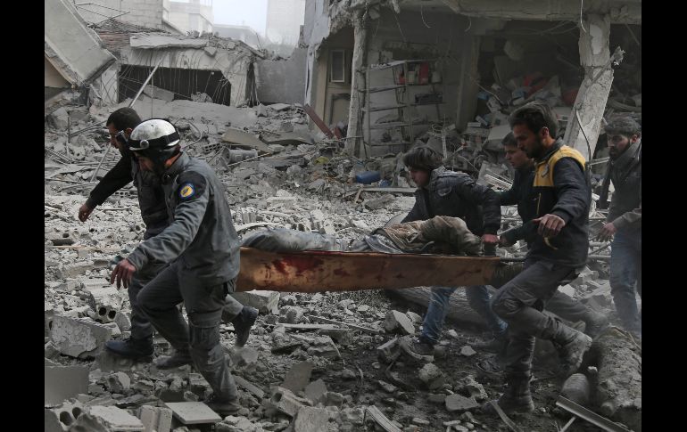 Miembros de la defensa civil siria evacuan a un herido de una zona bajo ataque aéreo en la población de Saqba, bajo control de los rebeldes. AFP/A. Eassa