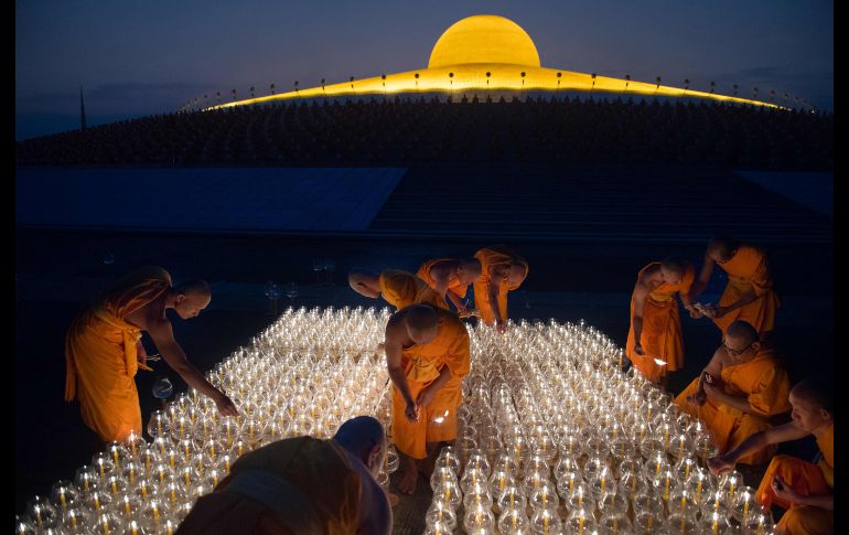 Monjes encienden velas en un templo en Bangkok, Tailandia, para las oraciones del día 