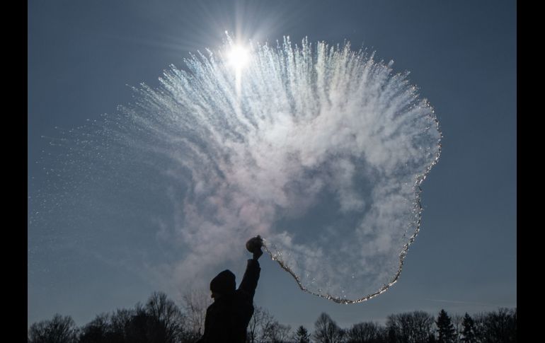 Una mujer arroja agua caliente que se congela al entrar en contacto con el frío en Berlin, Alemania.