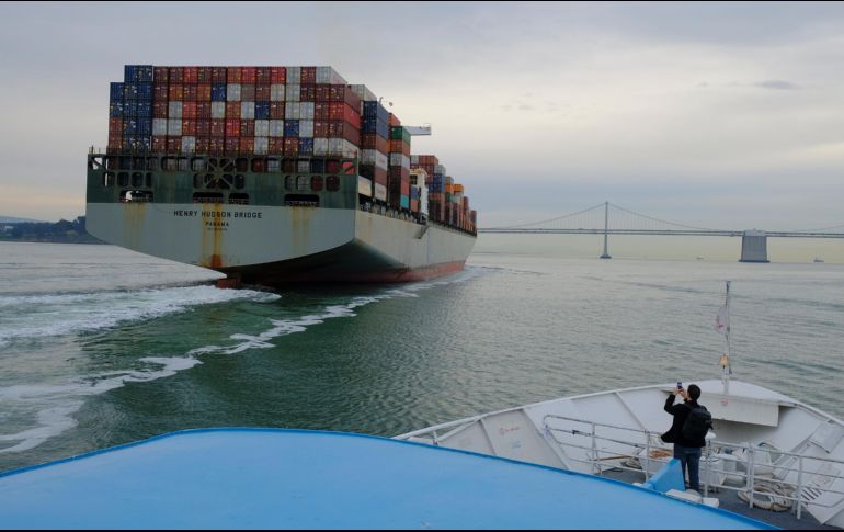 Un hombre toma una foto de un barco de contentedores que se dirige hacia el puente San Francisco-Oakland Bay en la ciudad estadounidense de San Francisco. AP/E. Risberg