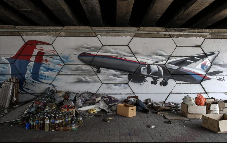 Un hombre descansa junto a un mural del vuelo desaparecido de Malaysia Airlines en Shah Alam, a las afueras de Kuala Lumpur. EFE/ARCHIVO