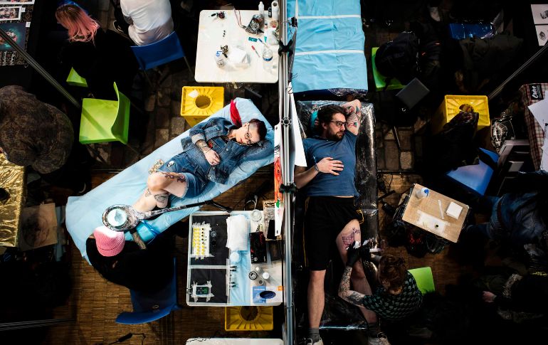 Tatuadores trabajan en la convención de tatuajes en París, que se realiza del 9 al 11 de marzo. AFP/P. Lopez